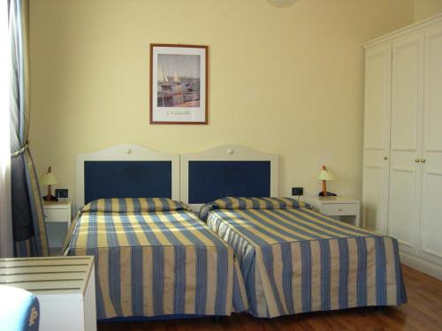 モンテカティーニ・テルメにあるHotel Brennero e Varsaviaのベッドルーム1室(ストライプシーツ付きのベッド2台付)