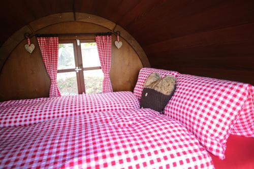 Una cama con sábanas rojas y blancas a cuadros y una ventana en Schlaf-Fass Maienfeld, en Maienfeld