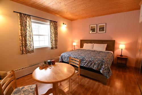 a bedroom with a bed and a table and a window at Kaleido Lodge Yukon in Whitehorse