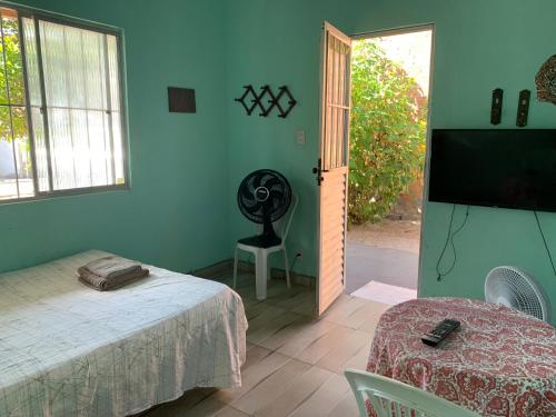 Habitación con cama, ventilador y TV. en Pousadinha da Lulu - Pontal Mangue Seco, en Indiaroba