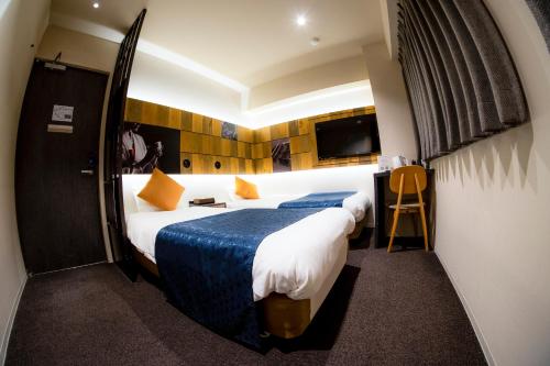 a hotel room with two beds and a tv at Hotel S-Presso Namba in Osaka