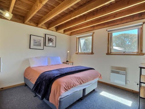 a bedroom with a bed and two windows at Banjo's Chalet, alpine-getaways in Dinner Plain