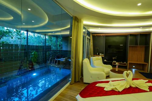 a bedroom with a pool and a bed and a tub at Kuruva Island Resort And Spa - By KABINI BREEZE in Mananthavady