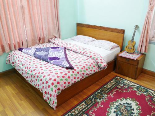 a bedroom with a bed with a guitar and a rug at Delights Home in Kathmandu