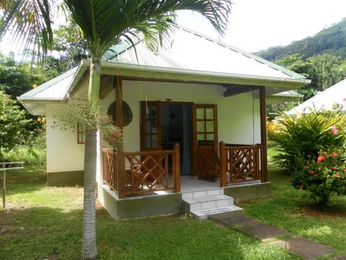 a small house with a porch and a palm tree at La Digue Ylang Ylang in La Digue