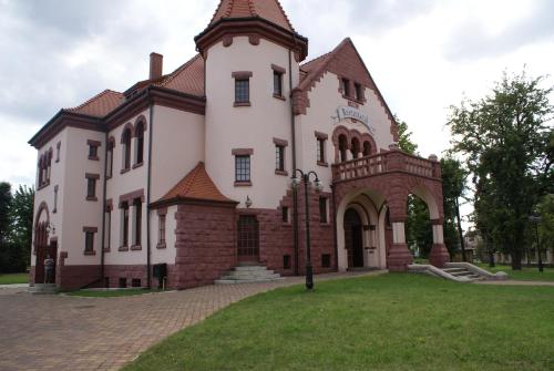 a large white building with a tower on a lawn at Villa Bergera in Dzierżoniów