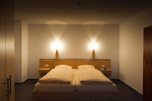a bedroom with two beds and two lights on the wall at Hotel Haus Deutsch Krone in Bad Essen