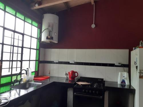 uma cozinha com um fogão, um lavatório e um balcão em La Casa De La Gruta em Mina Clavero