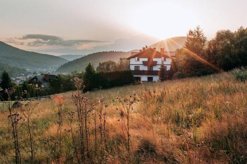 a house on the side of a hill with the sunset at Przystanek Góry in Szczyrk