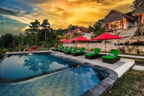 a resort swimming pool with green chairs and red umbrellas at NG Sweet Home in Nusa Penida