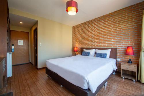 a bedroom with a large bed and a brick wall at WE Valley Hotel in Chiang Mai