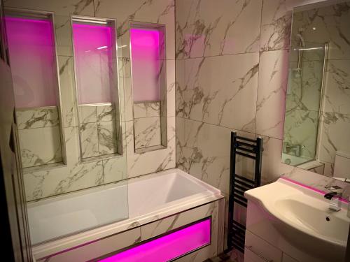 a bathroom with a tub and a sink with pink lights at Saltrock luxury apartment in Blackpool