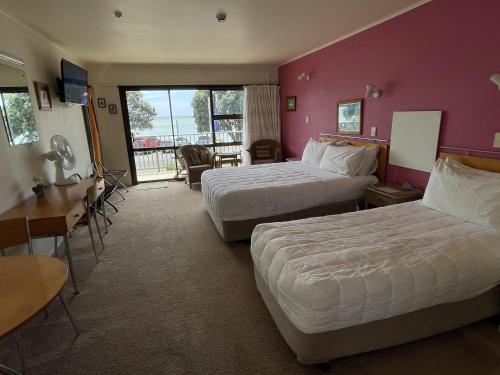 a hotel room with two beds and a balcony at Bay Sands Seafront Studios in Paihia