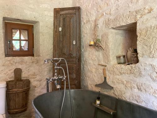 La salle de bains est pourvue d'une baignoire et d'un mur en pierre. dans l'établissement Les 2 Brigards, à Monestier