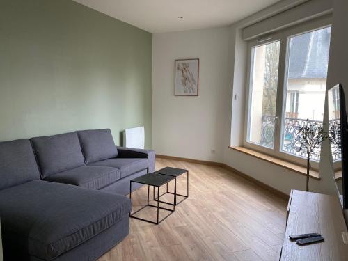 a living room with a couch and a large window at Superbe appartement Moderne Hyper centre de Vittel in Vittel