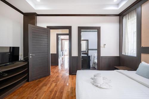 a bedroom with a white bed and a television at RimLay Beachfront Pool Villa in Sattahip