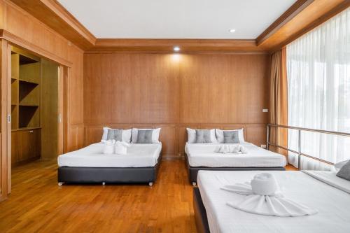 two beds in a room with wooden walls at RimLay Beachfront Pool Villa in Sattahip