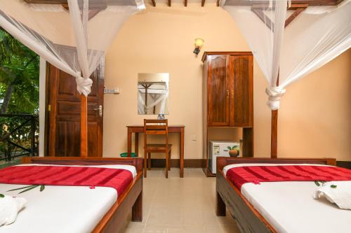 a bedroom with two beds and a desk in it at Amaan Beach Bungalows in Nungwi