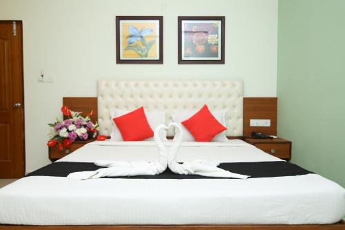 a bedroom with a large white bed with red pillows at Hotel Crystal Orchid in Bengaluru