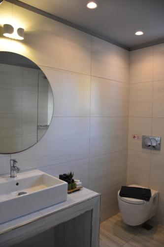a bathroom with a sink and a toilet and a mirror at De_naxia Suites in Perissa