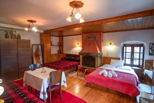 a bedroom with two beds and a table and a fireplace at Casa Calda in Syrrako