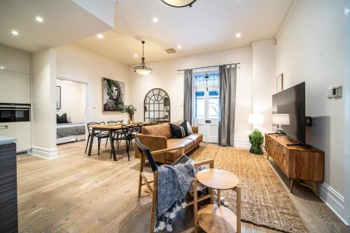 a living room with a couch and a table at Archer St Heart of North Adelaide Balcony 65TV in Adelaide