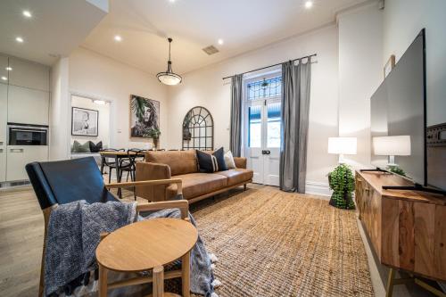 a living room with a couch and a table at Archer St Heart of North Adelaide Balcony 65TV in Adelaide