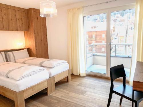 1 dormitorio con 2 camas, escritorio y ventana en Villa Emeline, en Zermatt