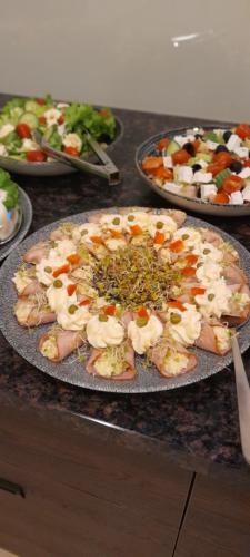 a pizza sitting on top of a counter with plates of food at Hotel Marusza in Grudziądz