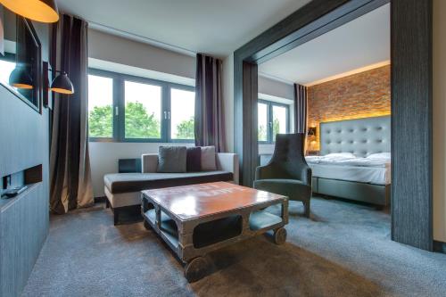 - un salon avec un lit, un canapé et une table dans l'établissement Park Inn by Radisson Lübeck, à Lübeck