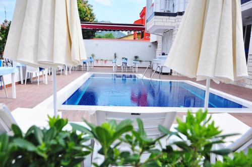 una piscina con sombrillas blancas, mesas y sillas en Amsterdam Otel & Suite Apart, en Kemer