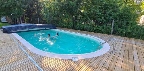 two people in a swimming pool on a wooden deck at Auberge de la Rivière in Foncine-le-Haut