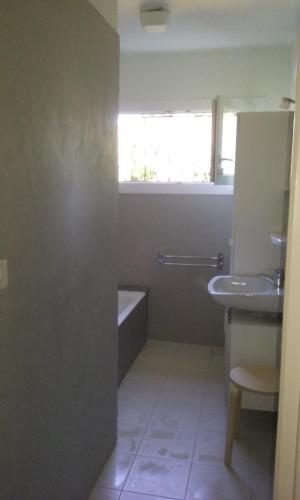 uma casa de banho com uma banheira, um lavatório e uma janela em MAISON PROVENCE AVEC PISCINE PRIVATIVE em Nyons