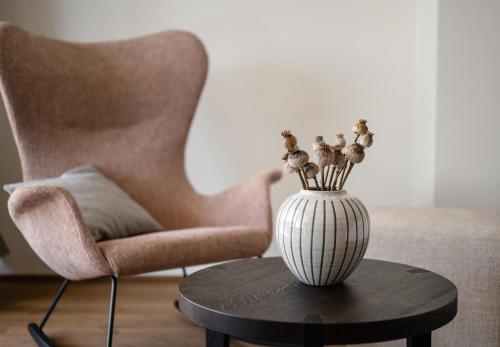 a vase with flowers on a table next to a chair at Hotel Mühlenerhof in Campo Tures