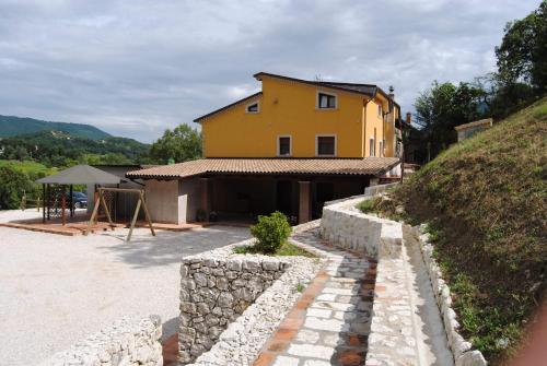 una casa amarilla con una pared de piedra delante de ella en B&B Pascale, en Cusano Mutri