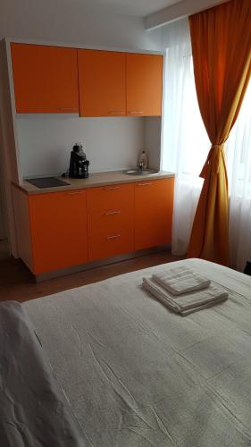 a kitchen with orange cabinets and a bed in a room at Apartament 4 Budiu in Târgu-Mureş