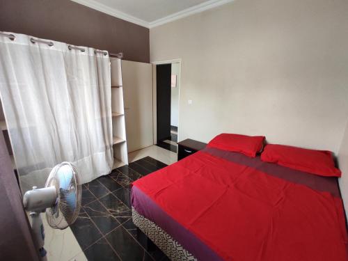 a bedroom with a red bed and a fan at Residence Jardin Tropical in Yaoundé