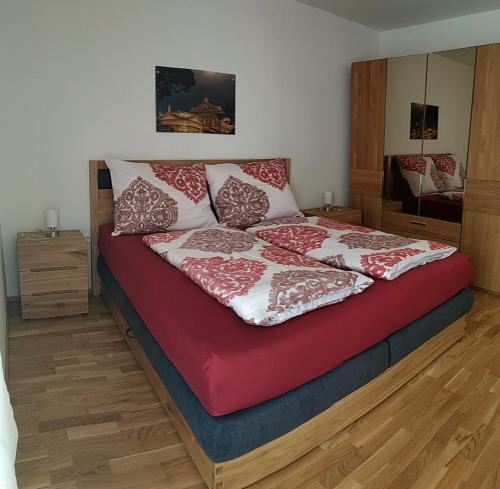 een bed met rode en witte kussens erop bij Albarosa Appartemant in Öblarn