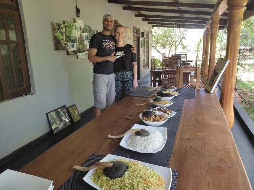 a man and woman standing next to a long table with food at Ceylon Resort in Wilpattu