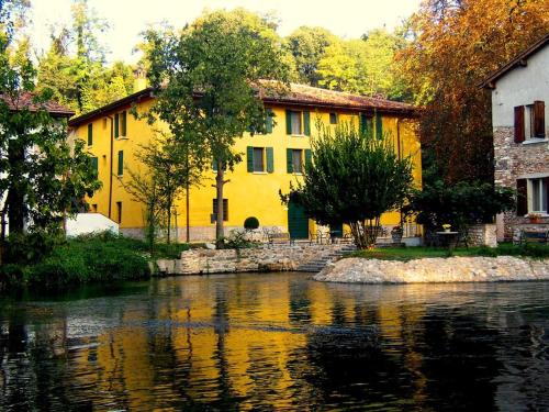 a yellow building next to a body of water at Villa dei Mulini in Volta Mantovana