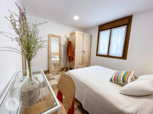 1 dormitorio con cama y mesa de cristal con jarrón en Casa Zunbeltz de 3 habitaciones en plena montaña, en Lezáun