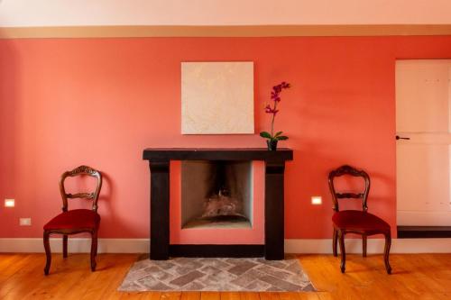 a living room with a fireplace and two chairs at Tenuta San Giorgio in Serravalle Scrivia