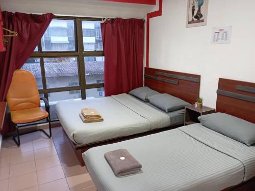 1 dormitorio con 2 camas, silla y ventana en Evonne Budget Hotel, en Tanah Rata