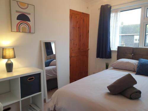 a bedroom with a bed and a mirror and a window at Stylish 3 Bedroom House with Free Parking in Norwich