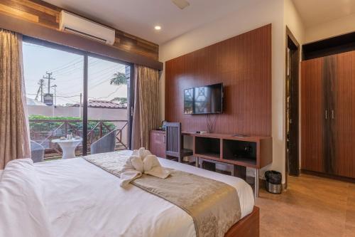 a bedroom with a large bed and a large window at Amara Oceanfront Resort & Club Baga in Baga