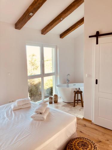 a white bedroom with a large bed and a bath tub at Villa Riba in Lun