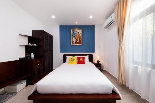 - une chambre avec un grand lit et un mur bleu dans l'établissement Chez Mimosa Boutique - New address 135 Tran Hung Dao, à Hô-Chi-Minh-Ville