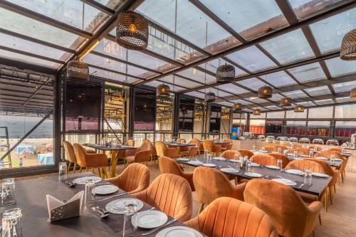 a dining room with tables and chairs and windows at Amara Oceanfront Resort & Club Baga in Baga