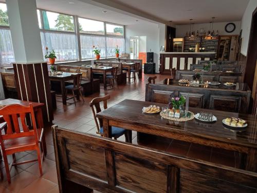 un restaurante con mesas y sillas de madera y ventanas en NEZNAŠOVY*** Restaurant-Penzion, en Vrhaveč