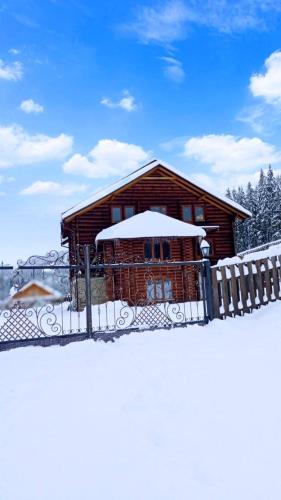 a log cabin with a fence in the snow at Villa Filiak in Yablunytsya